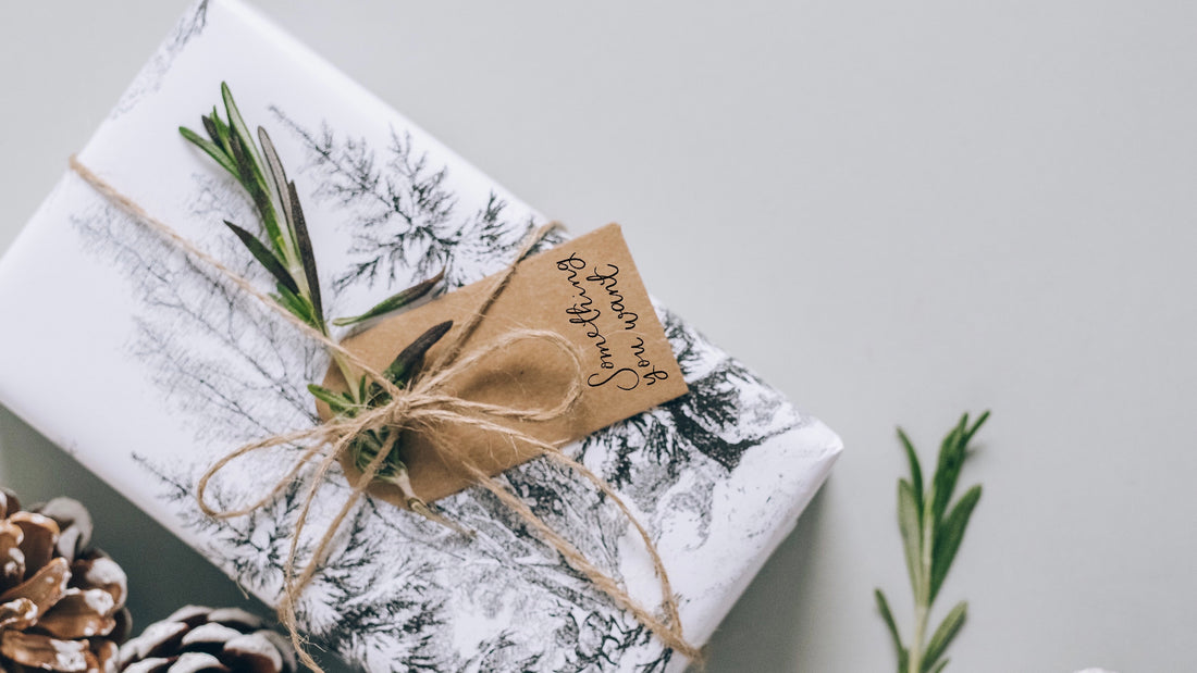 Christmas gift wrap with a something you need gift tag and a sprig of rosemary