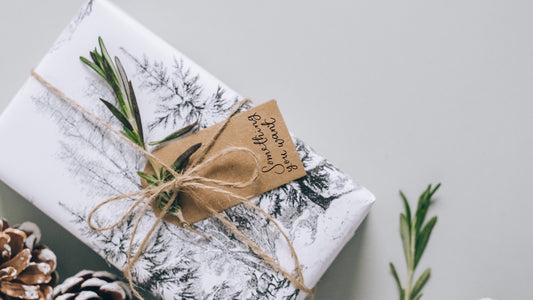 Christmas gift wrap with a something you need gift tag and a sprig of rosemary