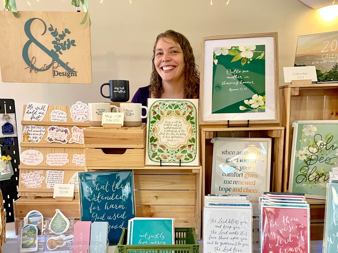 Anna of And Hope Designs smiling behind her stall at a craft fair in Belfast