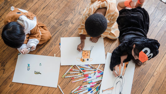 creative kids drawing pictures on paper spread across the floorthe 