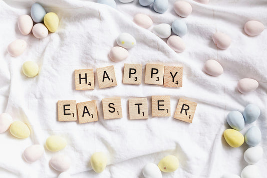 happy easter spelt out in scrabble tiles surrounded by pastel mini eggs