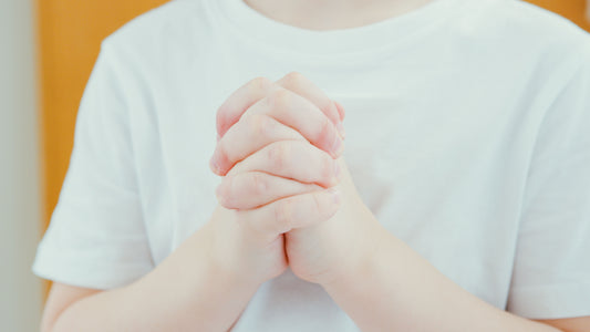 praying child with hands clasped in front of them