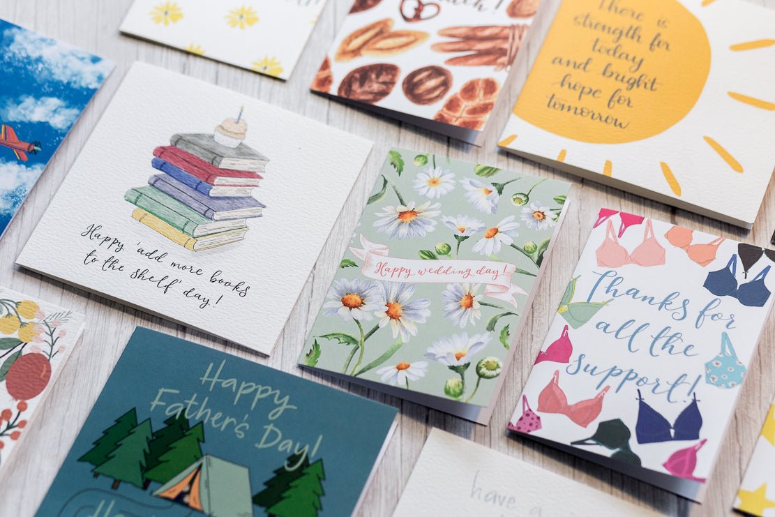 Bright and colourful Photo of a selection of And Hope Designs cards including a birthday card for book lovers, a wedding card, a Father’s Day card and a thank you card. 