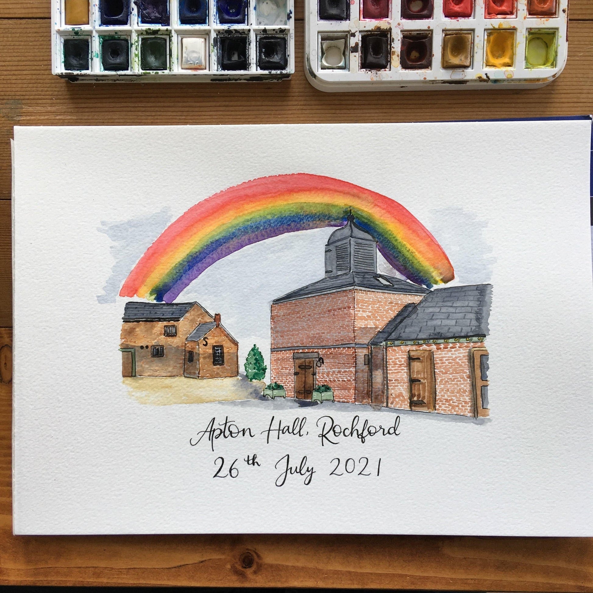 Wedding venue watercolour illustration with hand lettering below of the wedding venue name and date of the wedding. This painting also includes a bright rainbow.